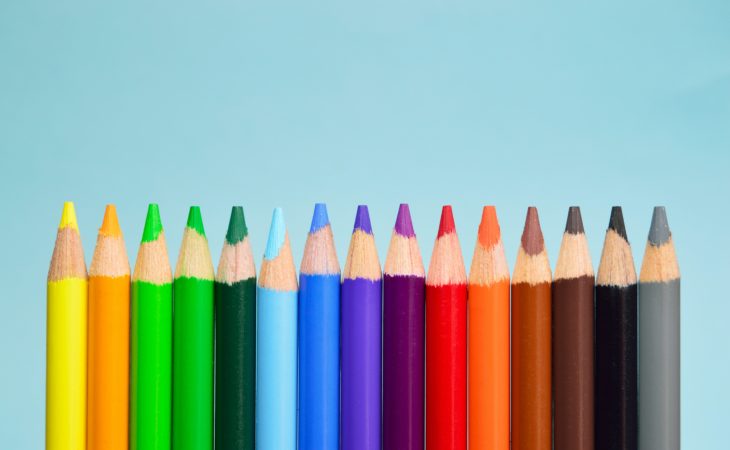 Fargeblyanter i alle regnbuens farger (inkludert svart, brunt og grått) mot en lysblå bakgrunn.